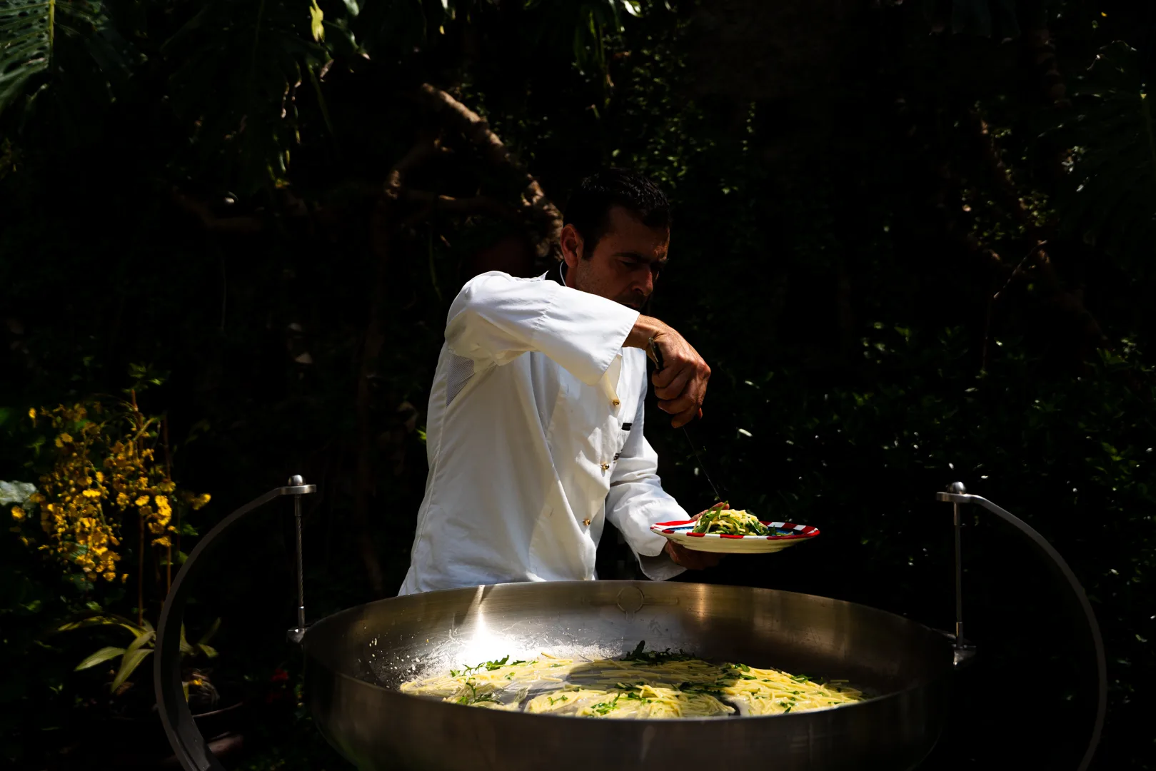 Lo chef impiatta la pasta appena cotta per il catering esterno