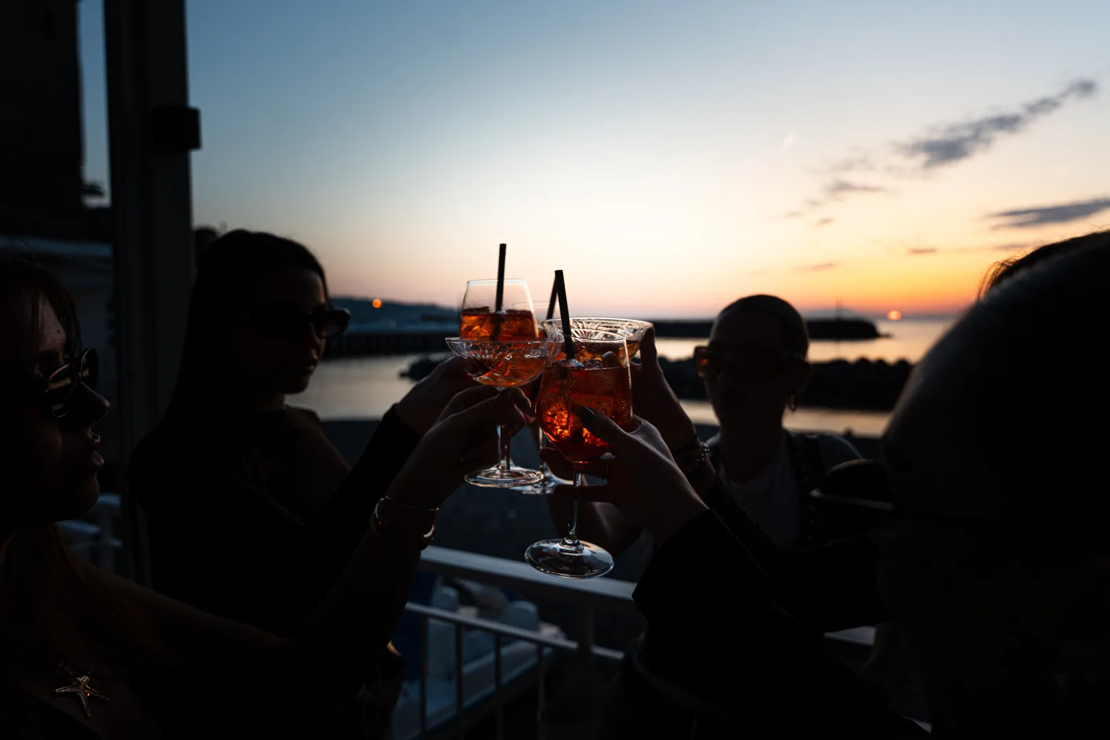 Amici brindano in terrazza al tramonto sul porto