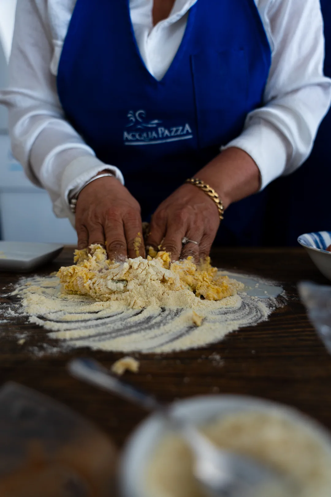 Mani che lavorano l'impasto con il logo Acquapazza